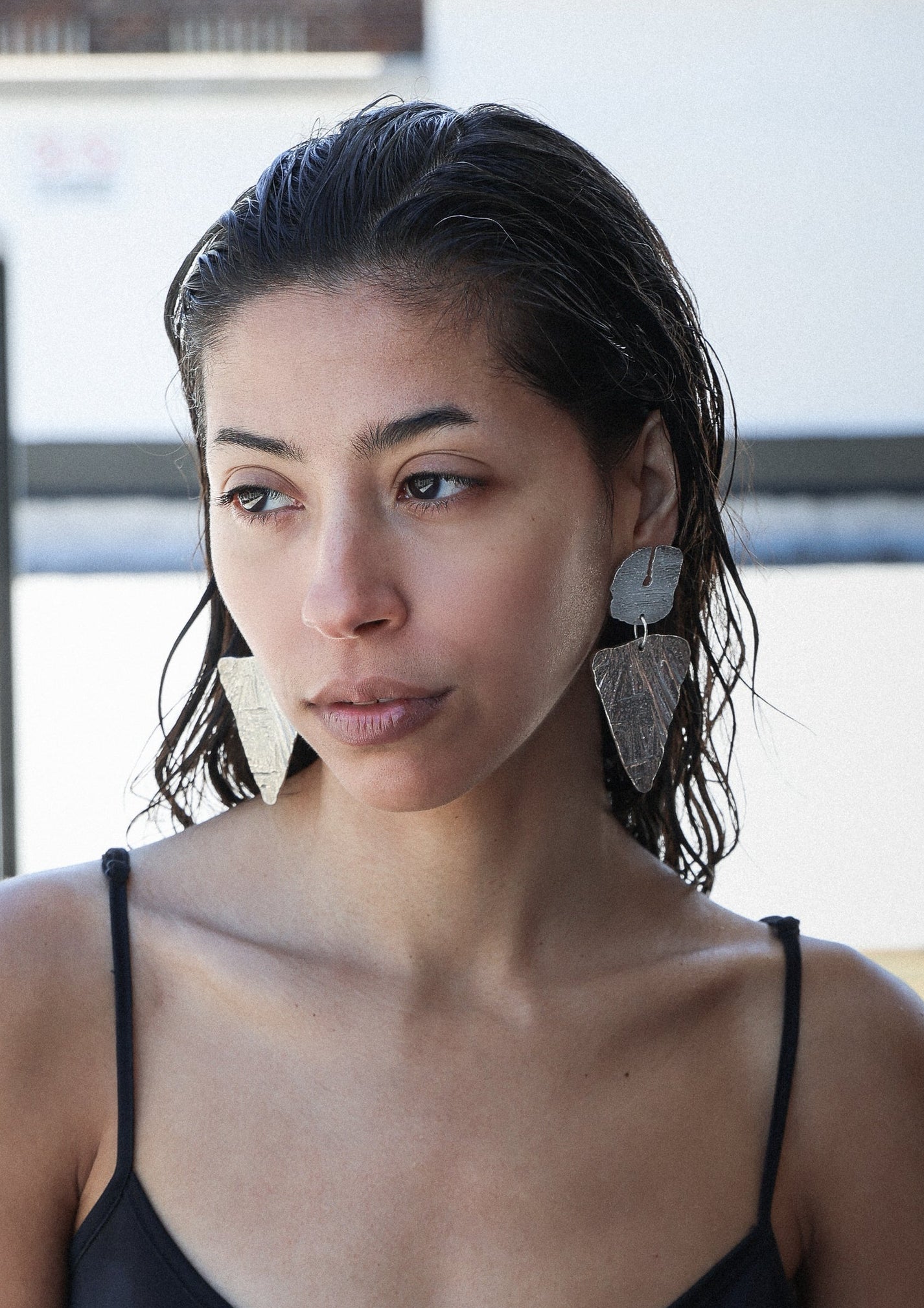 Woman of color wearing stunning silver earrings inspired by doritos created by hand and shipped from NYC.